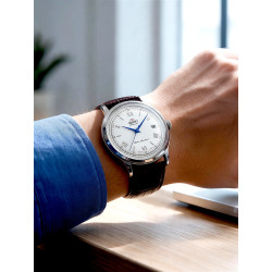 Zegarek garniturowy Orient Bambino TAC00009W0 na dłoni w błękitnej koszuli